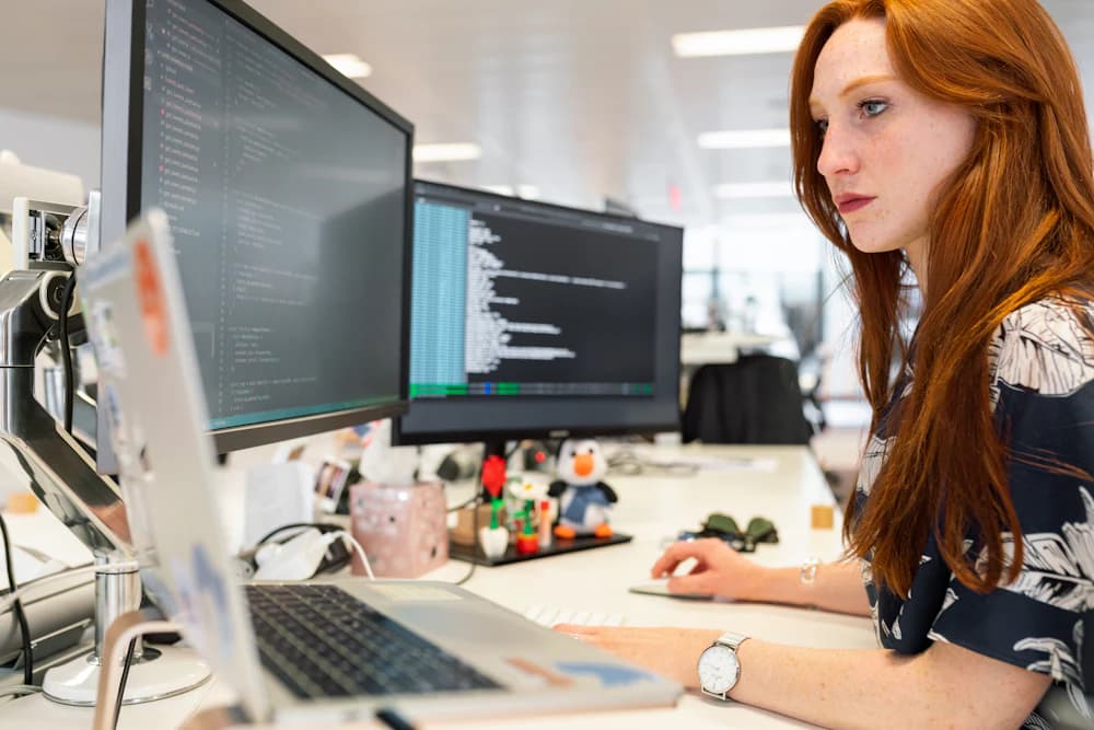 An engineer reviewing code across several monitors