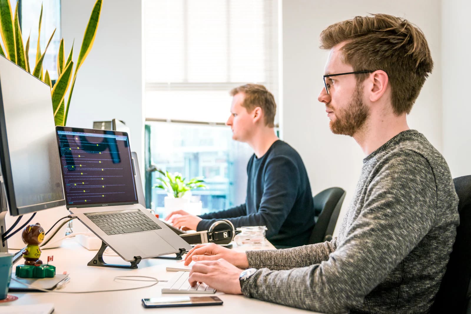 Two engineers working side by side at laptops in a bright studio